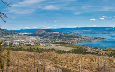 A mountain top view of a hillside and lakeside city.