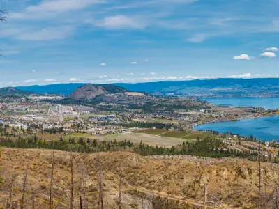 A mountain top view of a hillside and lakeside city.